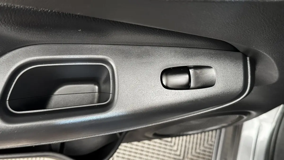 Détail de la poignée intérieure de porte côté conducteur du Nissan Juke Hybrid 143 Business+ gris foncé 2023.