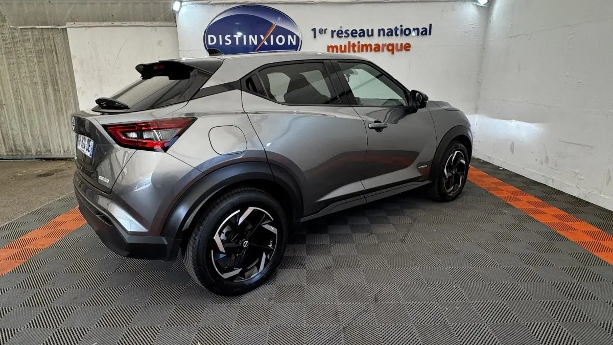 Nissan Juke Hybrid 143 Business+ gris foncé vu en 3/4 arrière droit avec jantes noires et toit noir.