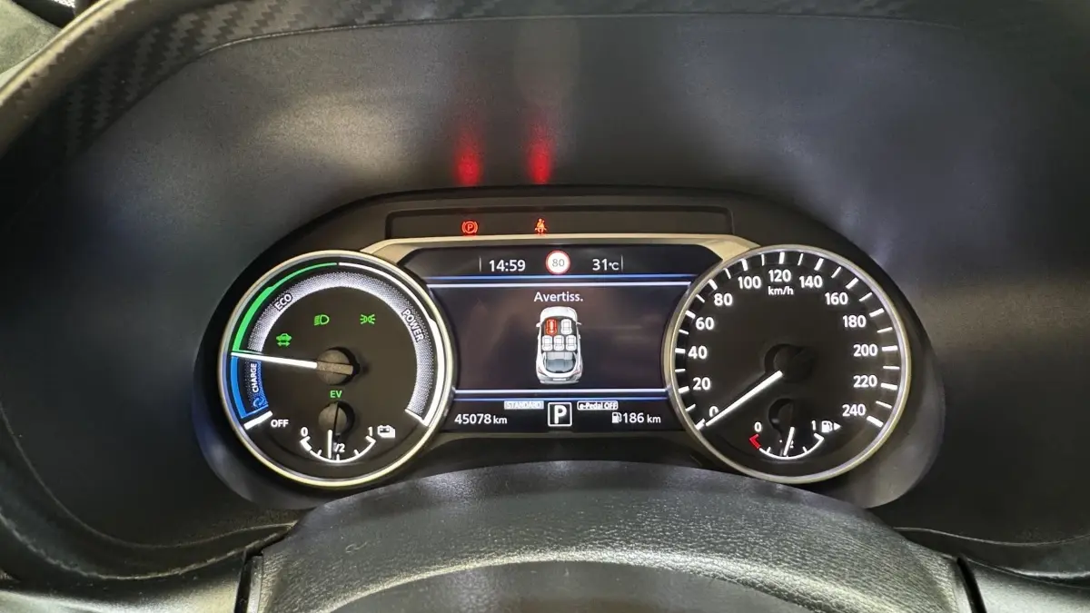 Vue rapprochée du combiné d'instruments numérique et analogique du Nissan Juke Hybrid 143 Business+ affichant une alerte de porte ouverte.