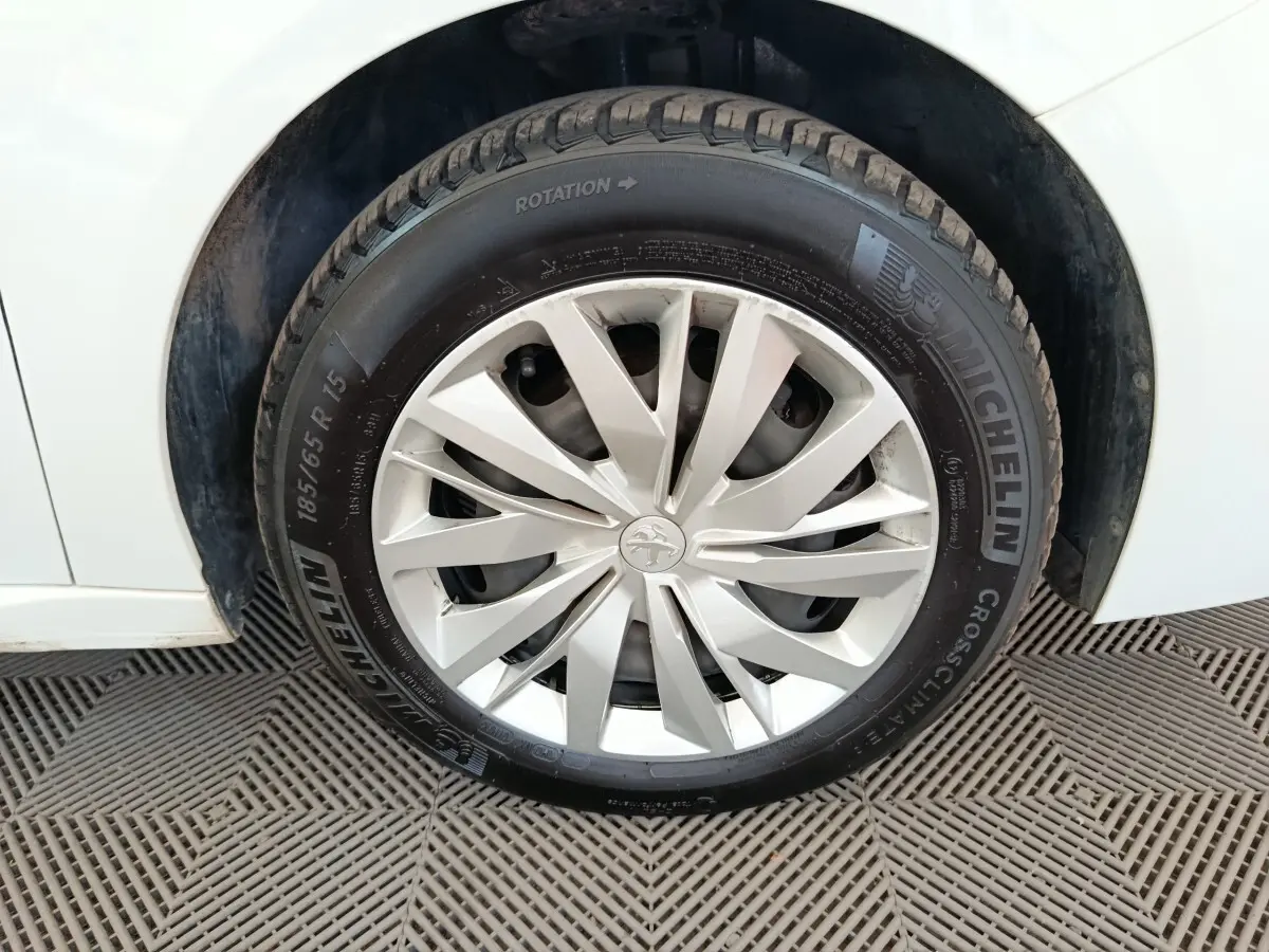Gros plan sur la roue avant gauche d'une Peugeot 208 blanche avec jante en alliage et pneu Michelin.