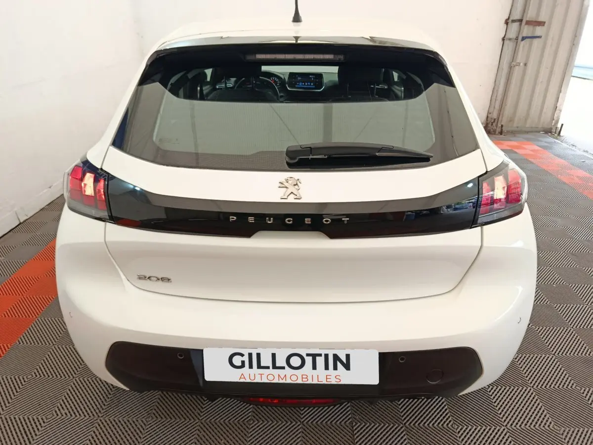 Vue arrière d'une Peugeot 208 blanche 2023 avec feux LED et logo Peugeot bien visibles.