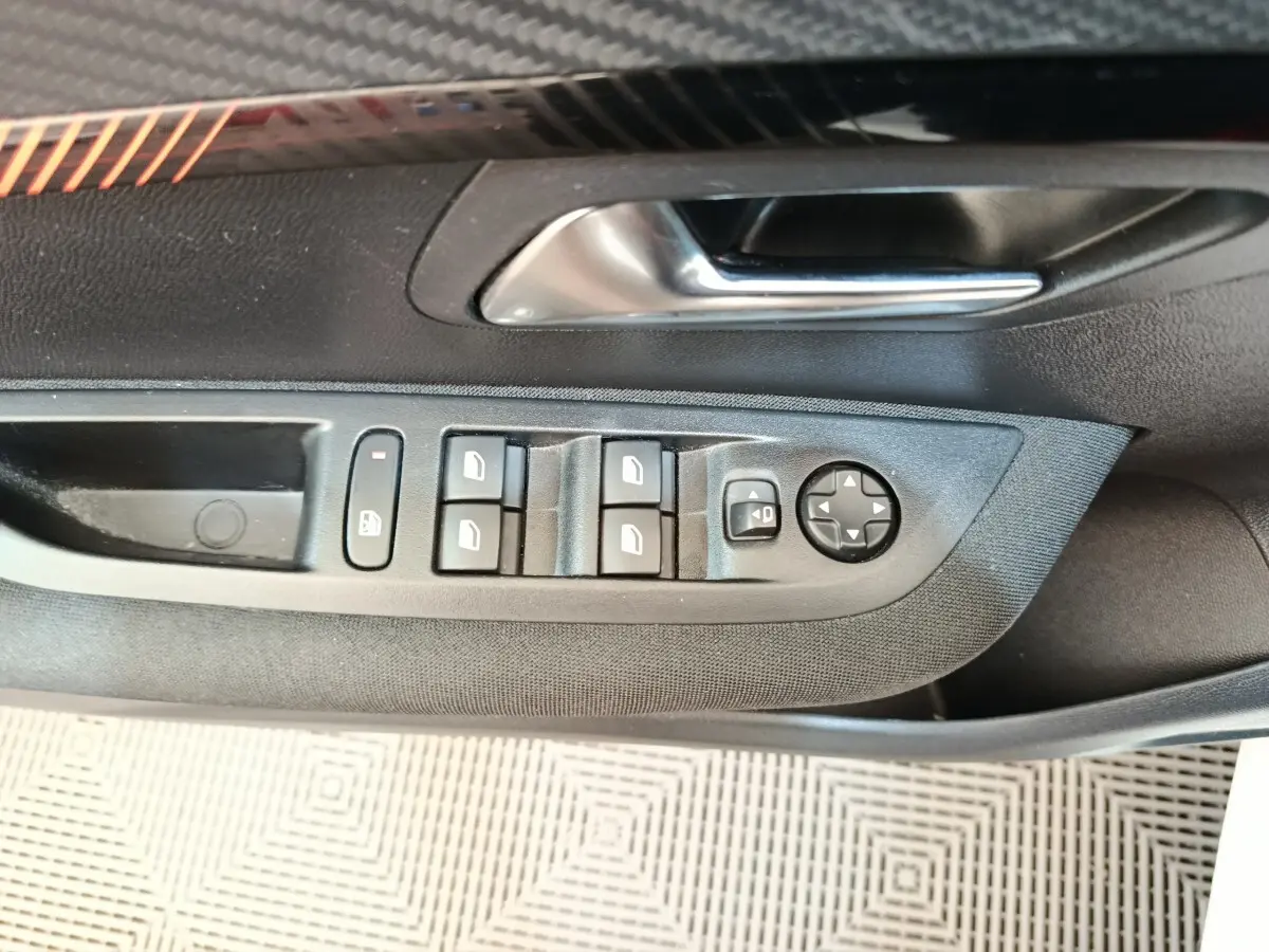 Gros plan sur la commande des vitres et rétroviseurs côté gauche intérieur d’une Peugeot 208 blanche 2023.