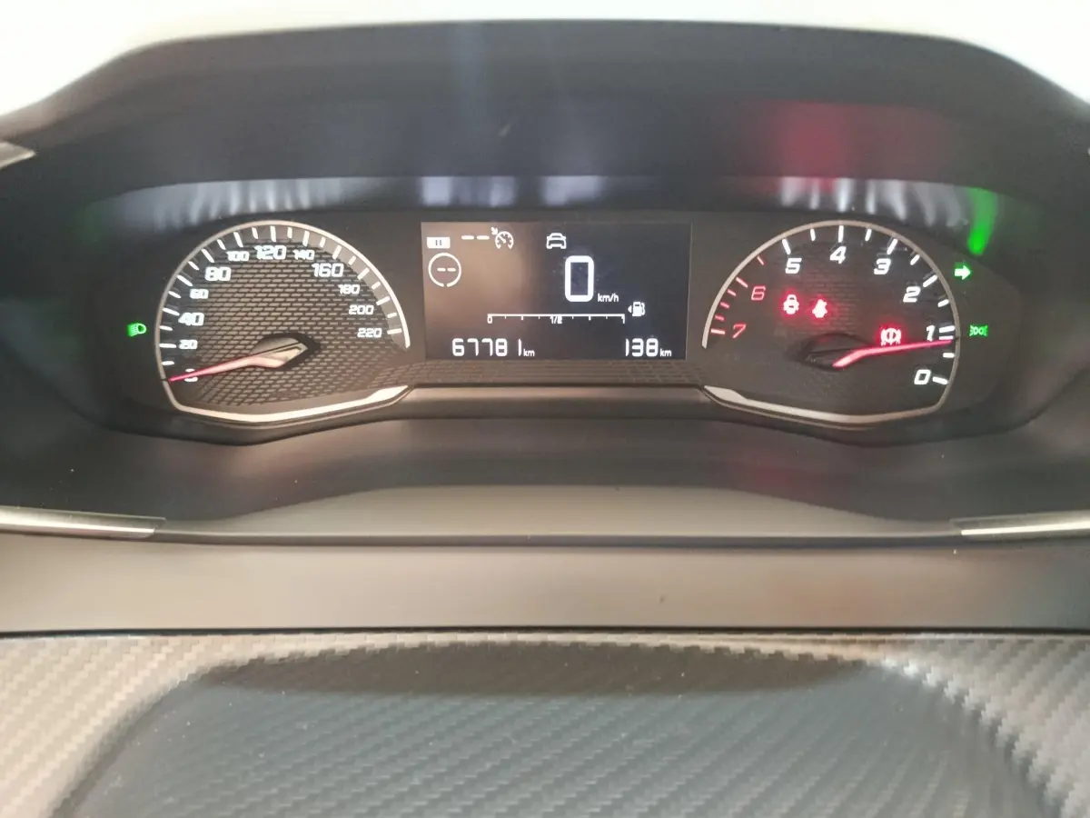 Vue rapprochée du tableau de bord numérique de la Peugeot 208 1.5 BlueHDi blanc, affichant la vitesse et le kilométrage.