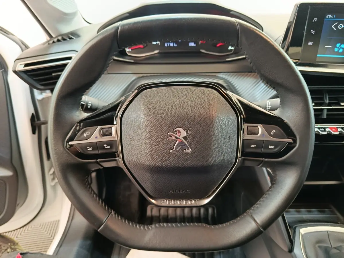 Vue rapprochée du volant cuir multifonctions noir de la Peugeot 208 1.5 BlueHDi 100 S&S Premium blanche de 2023.