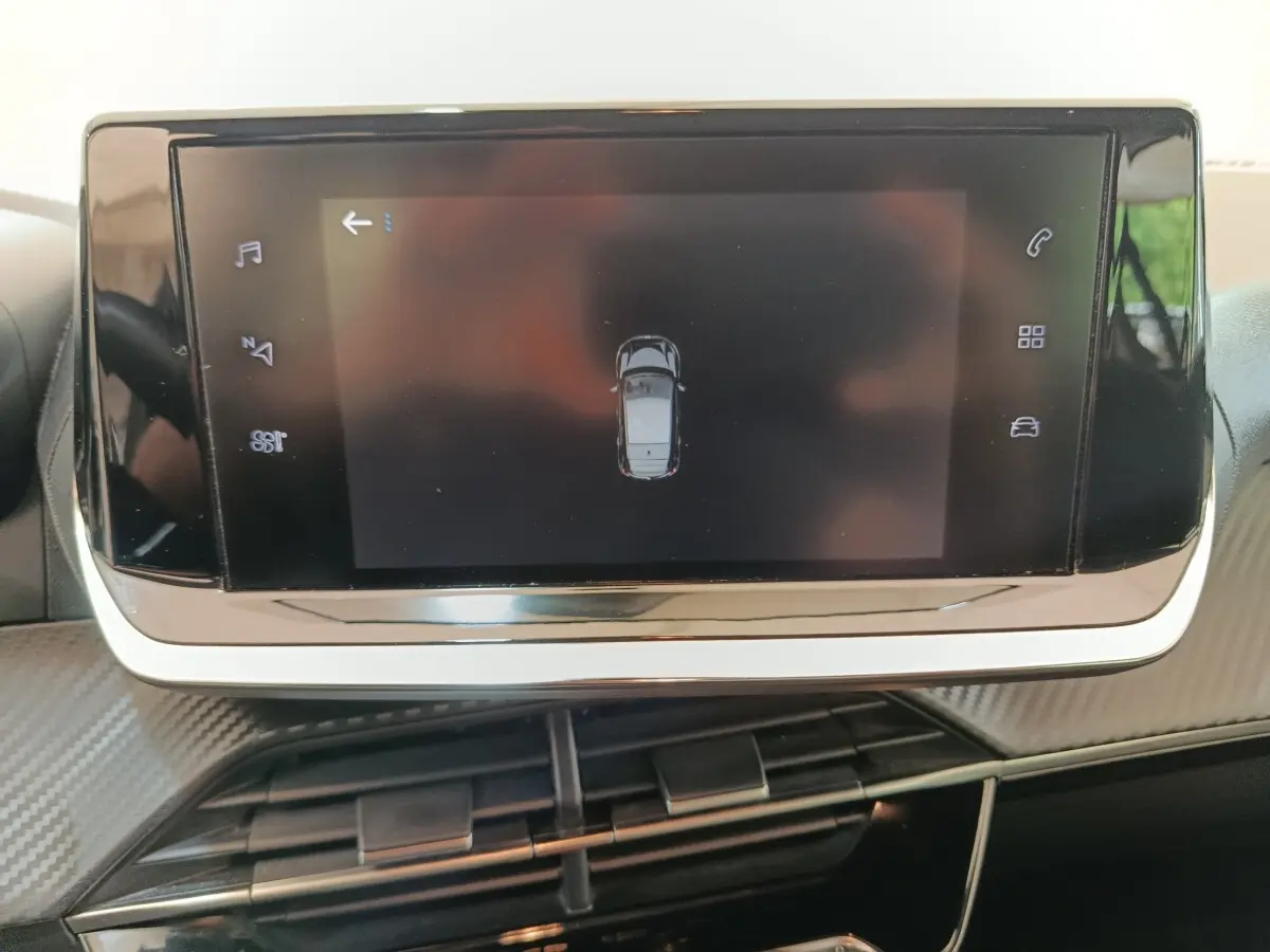 Écran tactile central affichant une vue aérienne du véhicule dans l'habitacle d'une Peugeot 208 blanche.