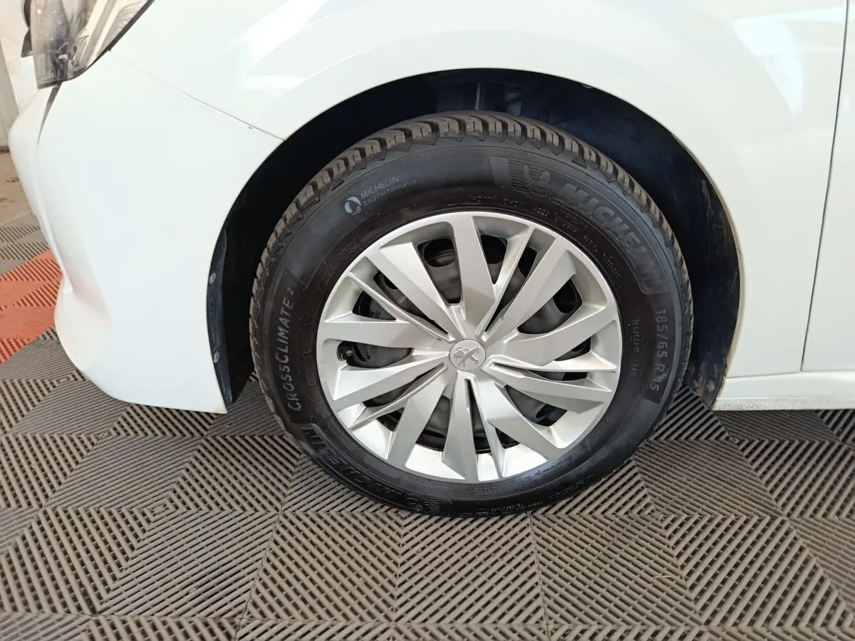 Gros plan sur la roue avant gauche blanche d'une Peugeot 208 1.5 BlueHDi 100 S&S Premium 2023.