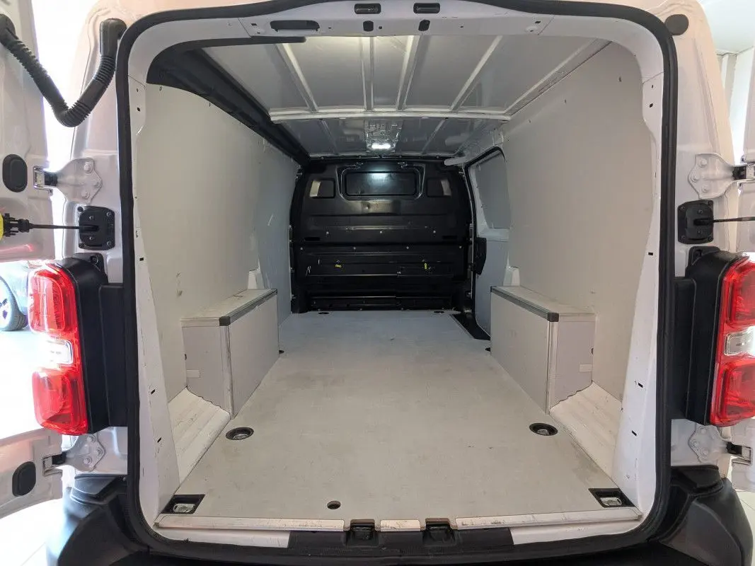 Vue arrière ouverte du fourgon FIAT Scudo XL blanc, montrant l'espace de chargement vide et les parois intérieures claires.