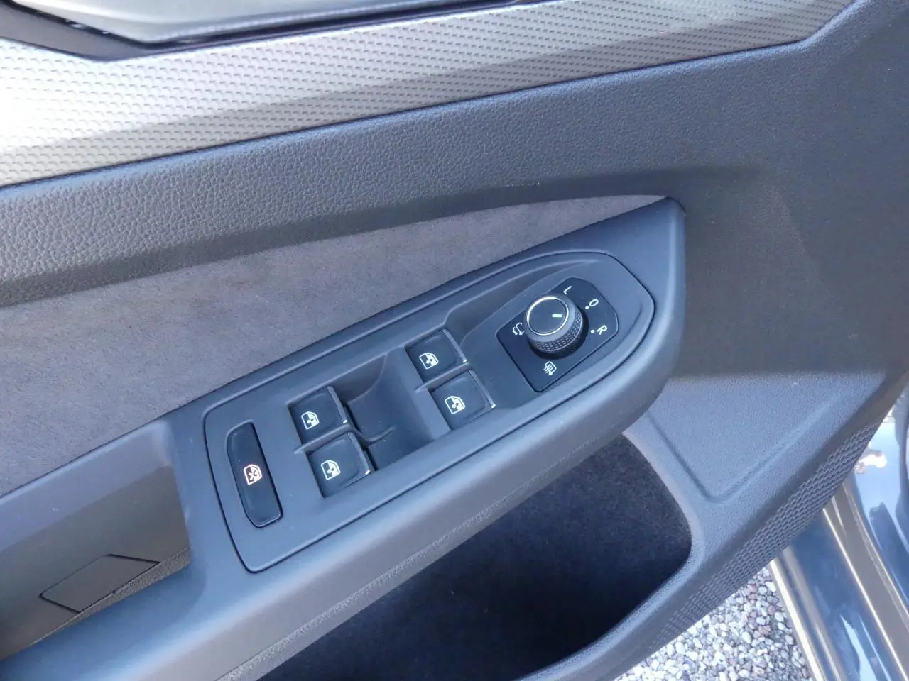 Commande des vitres et réglage des rétroviseurs sur la porte côté conducteur d'une Volkswagen Golf gris métallisé 2024