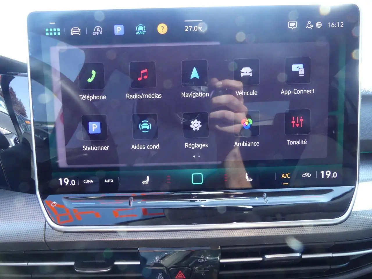 Écran tactile central de la Volkswagen Golf 1.5 eTSI 2024 affichant les menus de navigation et réglages, intérieur noir.