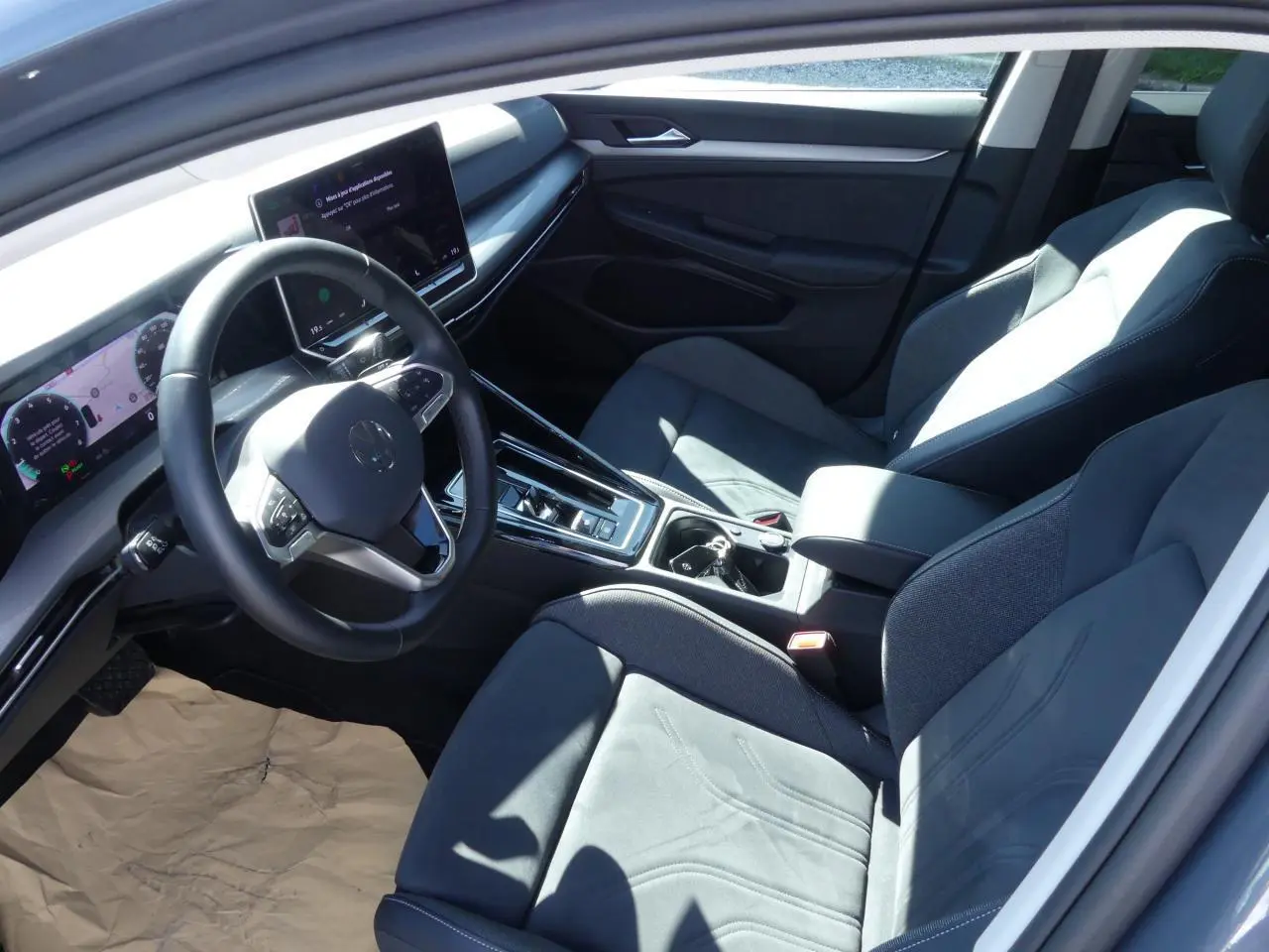 Intérieur avant côté conducteur de Volkswagen Golf 2024 avec sièges microfleece gris et tableau de bord digital.