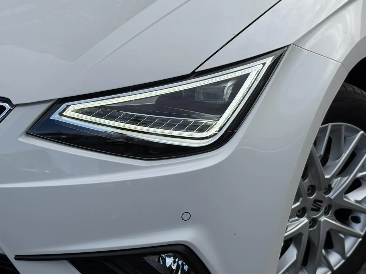 Gros plan sur le phare avant droit et la jante alliage 16 pouces d'une SEAT Ibiza blanche 2025 finition Xcellence.