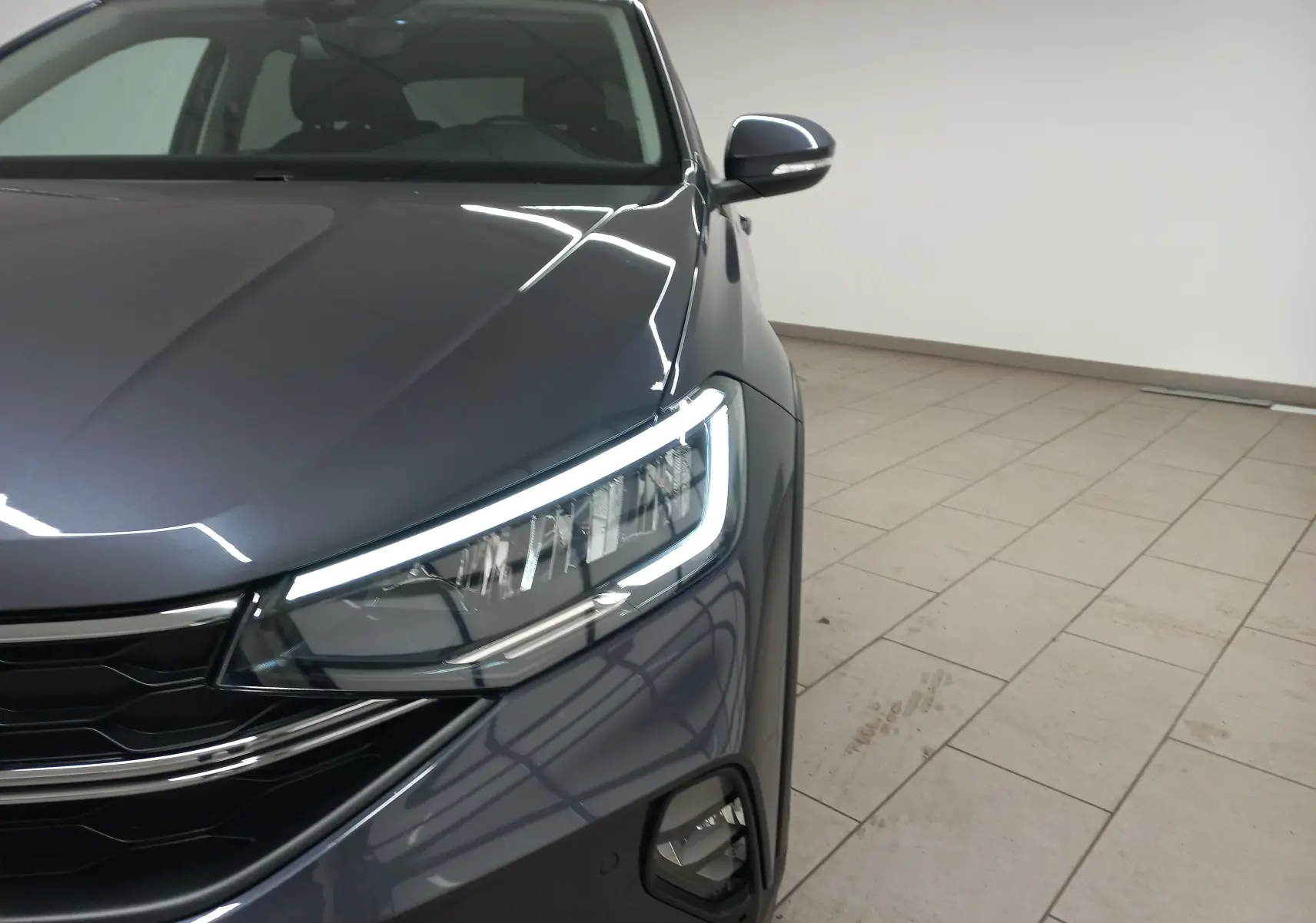 Gros plan sur l'avant droit du Volkswagen Taigo gris cendré, mettant en valeur les phares LED et le projecteur antibrouillard.