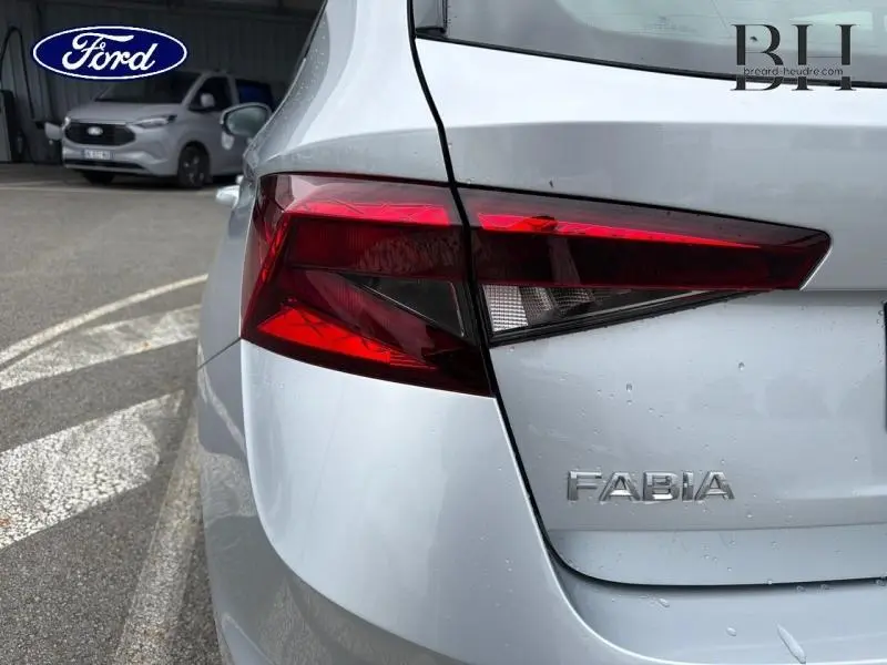 Gros plan sur le feu arrière droit d'une Skoda Fabia gris argent métallisé avec logo et détails de la carrosserie visibles.