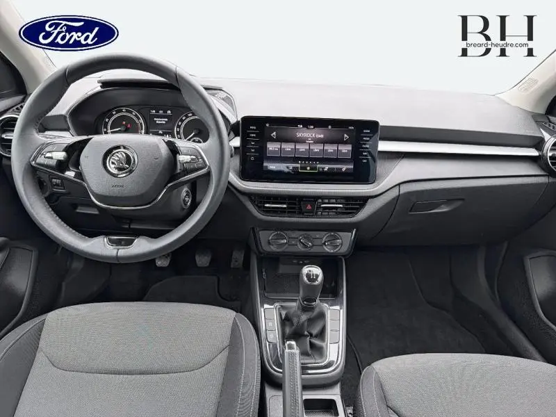 Intérieur avant de la Skoda Fabia 1.0 MPI 80ch Ambition 2023, vue centrée sur tableau de bord et volant noir.