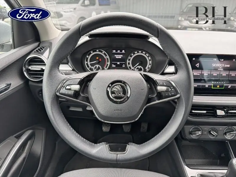 Vue intérieure centrée sur le volant cuir de la Skoda Fabia gris argent, avec tableau de bord et écran tactile visibles.