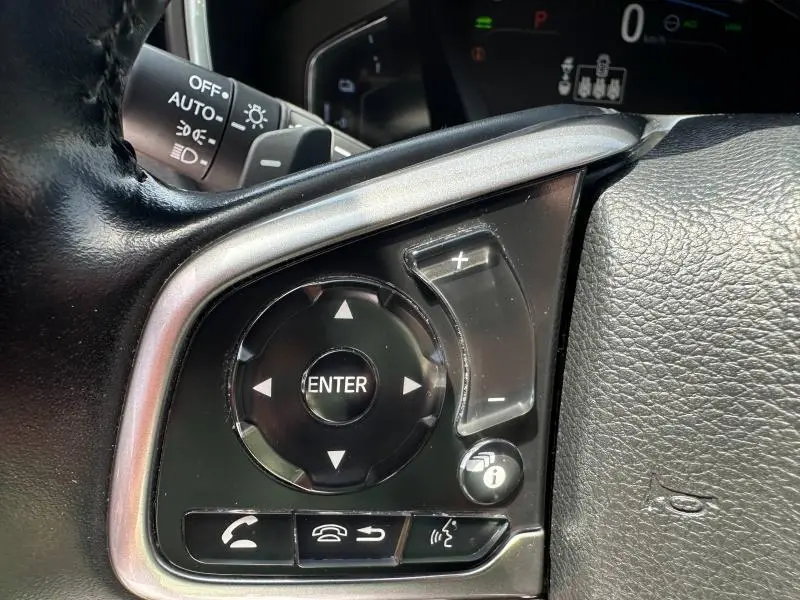 Gros plan sur les commandes multifonctions noires du volant cuir du Honda CR-V 2020, avec touches de volume et navigation.