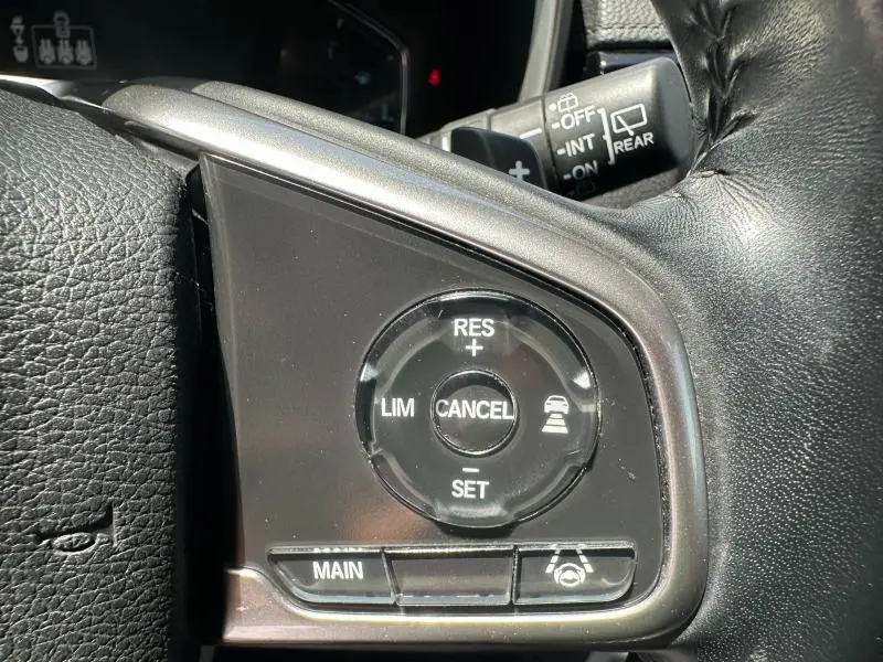 Gros plan sur les commandes du régulateur de vitesse au volant cuir noir du Honda CR-V rouge Rallye, version Executive 2020.