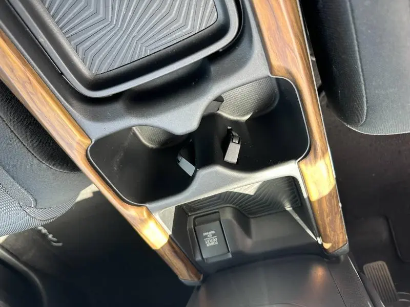 Gros plan sur la console centrale intérieure du Honda CR-V 2020 avec inserts bois et porte-gobelets noirs.