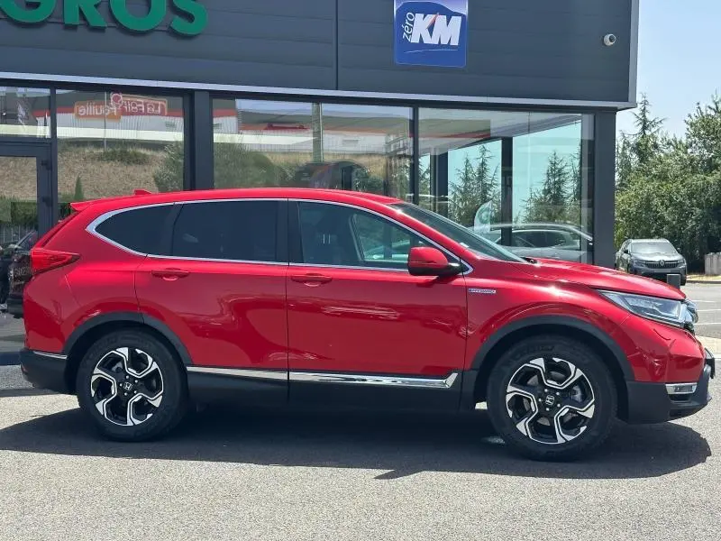 Vue de profil côté gauche d'un Honda CR-V rouge Rallye avec jantes alliage et vitres arrière surteintées.