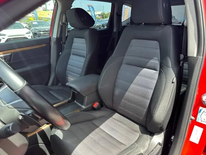 Vue intérieure du Honda CR-V rouge Rallye 2020, mettant en valeur les sièges avant en tissu noir avec accoudoir central.