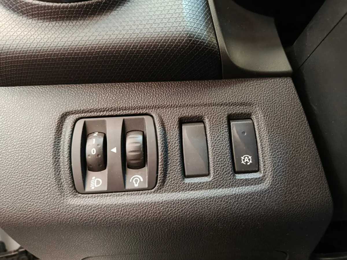 Gros plan sur les commandes de réglage des phares et de l'éclairage intérieur côté gauche d'une Renault Clio blanche 2018.