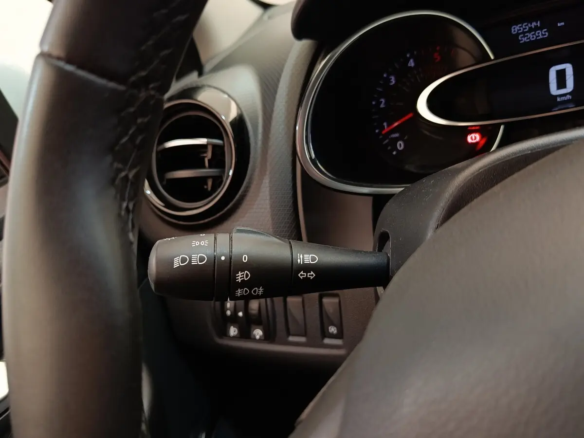 Gros plan sur la manette des feux à gauche du volant cuir dans l’habitacle d’une Renault Clio Business blanc 2018.