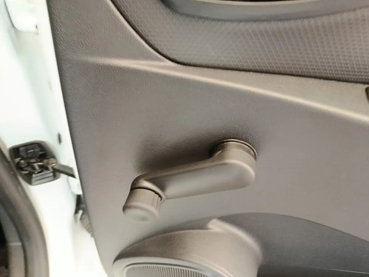 Poignée de manivelle de vitre côté gauche sur porte intérieure noire d’une Renault Clio blanche 2018.