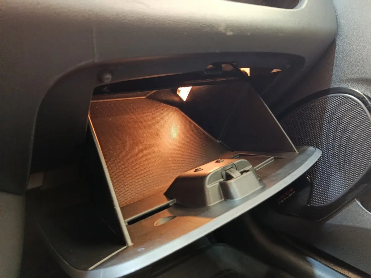 Vue rapprochée de la boîte à gants ouverte avec éclairage intérieur dans une Renault Clio Business dCi 75 blanche de 2018.