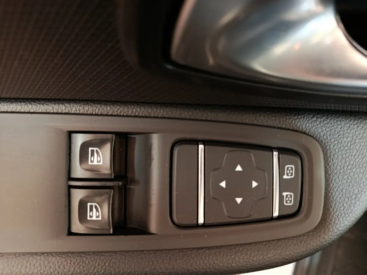 Gros plan sur les commandes de réglage des vitres et des rétroviseurs côté conducteur d’une Renault Clio Business blanc 2018.