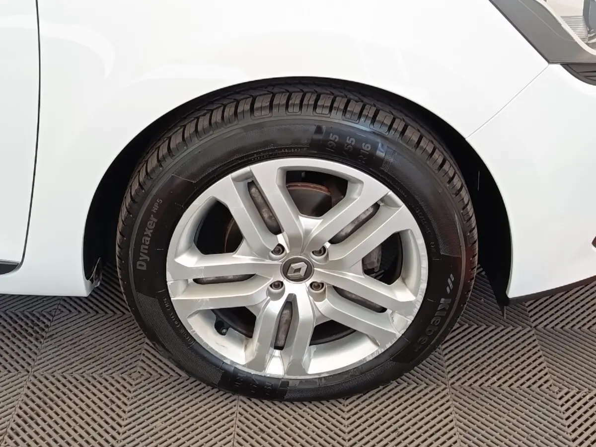 Gros plan sur la roue avant droite d’une Renault Clio blanche, avec jante alliage et logo Renault central.