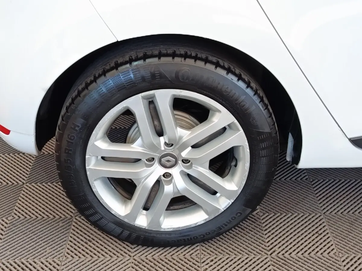 Gros plan sur la roue arrière droite blanche d’une Renault Clio Business dCi 75 avec jante alliage argentée.