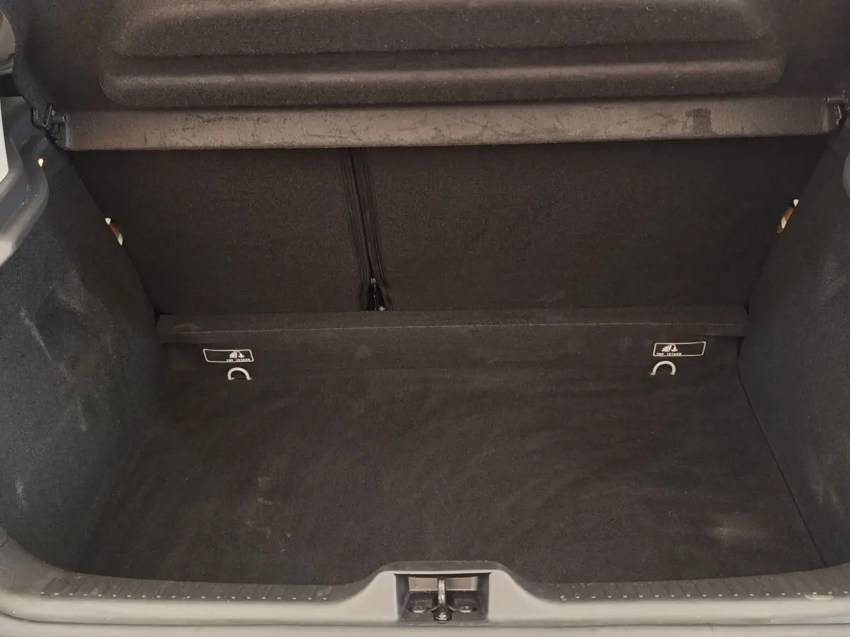Coffre ouvert de la Renault Clio Business dCi 75 blanc, montrant l'espace de chargement vide et la moquette noire.