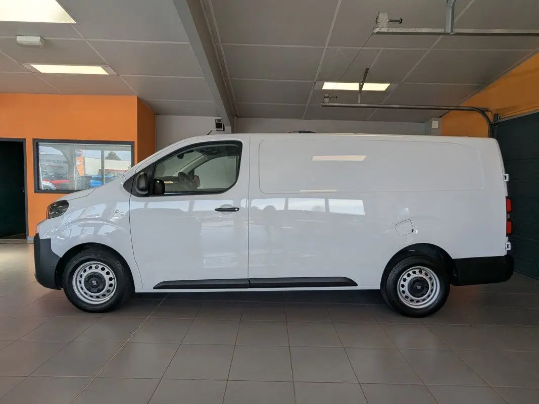 Vue de profil côté gauche du fourgon FIAT Scudo XL blanc avec jantes tôles grises 17 pouces en intérieur showroom.