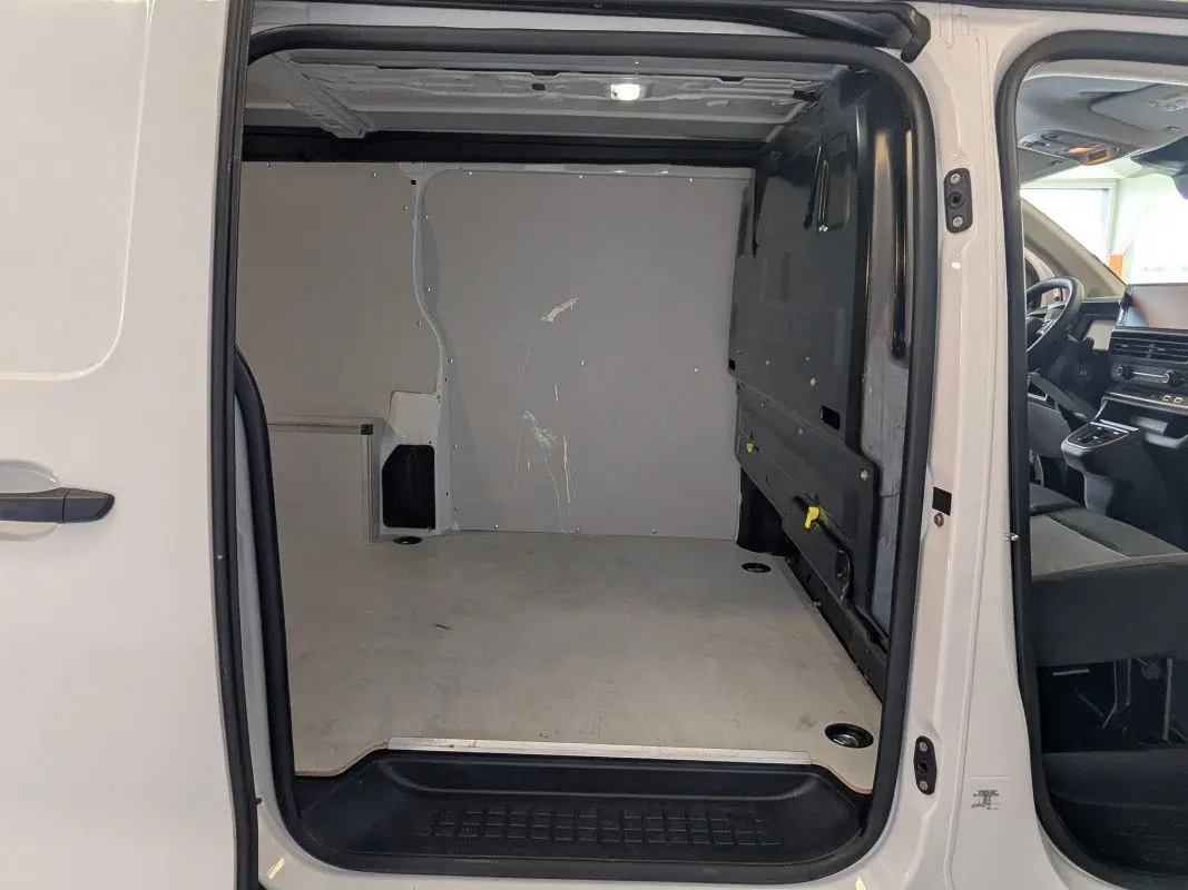 Vue intérieure du coffre blanc du FIAT Scudo Fourgon XL 145 EAT8 2025 avec porte latérale ouverte à 180 degrés.