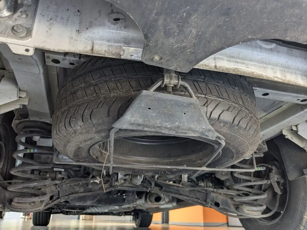 Vue en contre-plongée sous un FIAT Scudo Fourgon blanc, montrant la roue de secours suspendue sous le châssis.