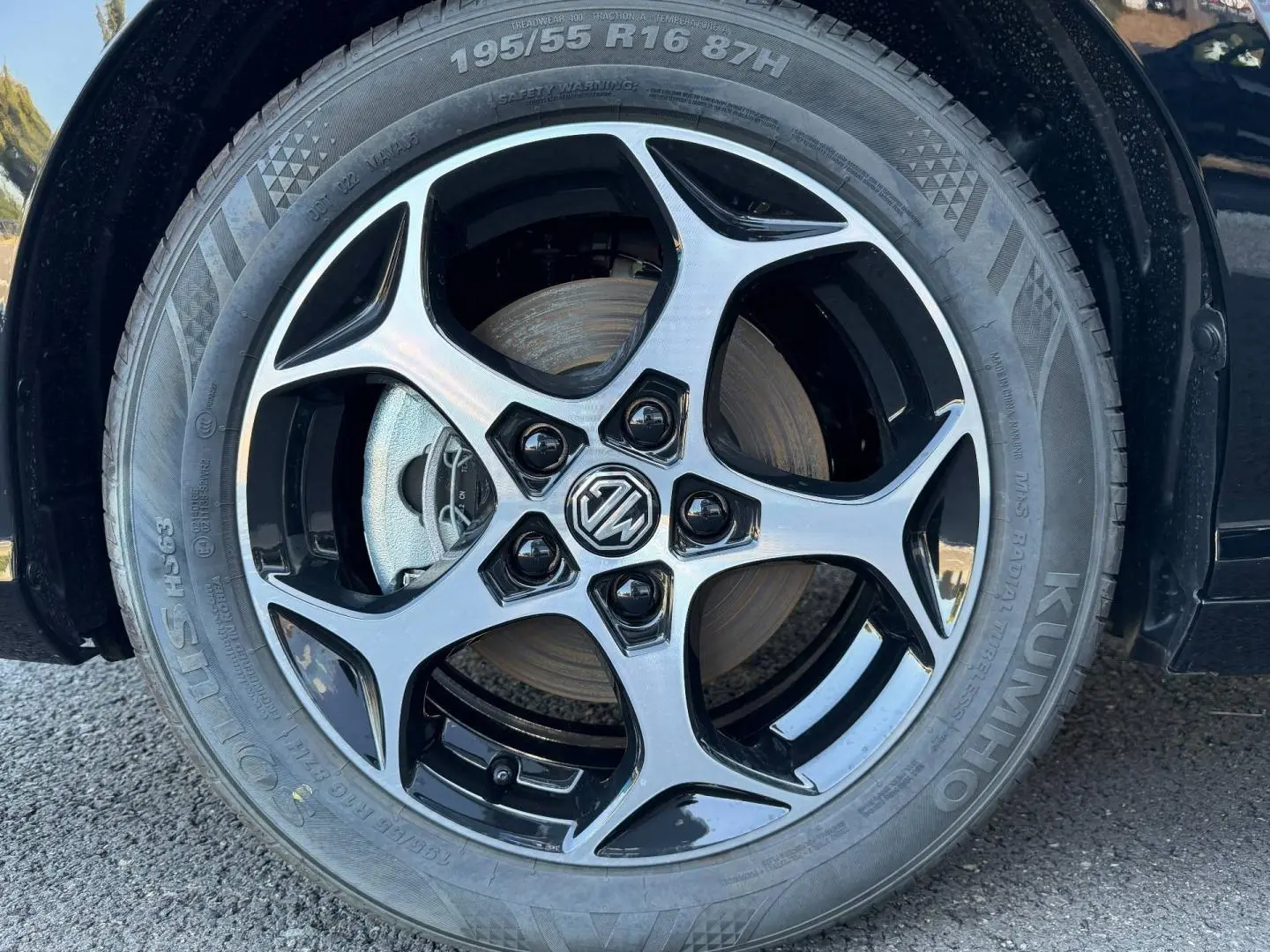 Gros plan sur la jante alu noire et argentée avec logo MG d'une MG3 Pebble Black métallisé, côté gauche.