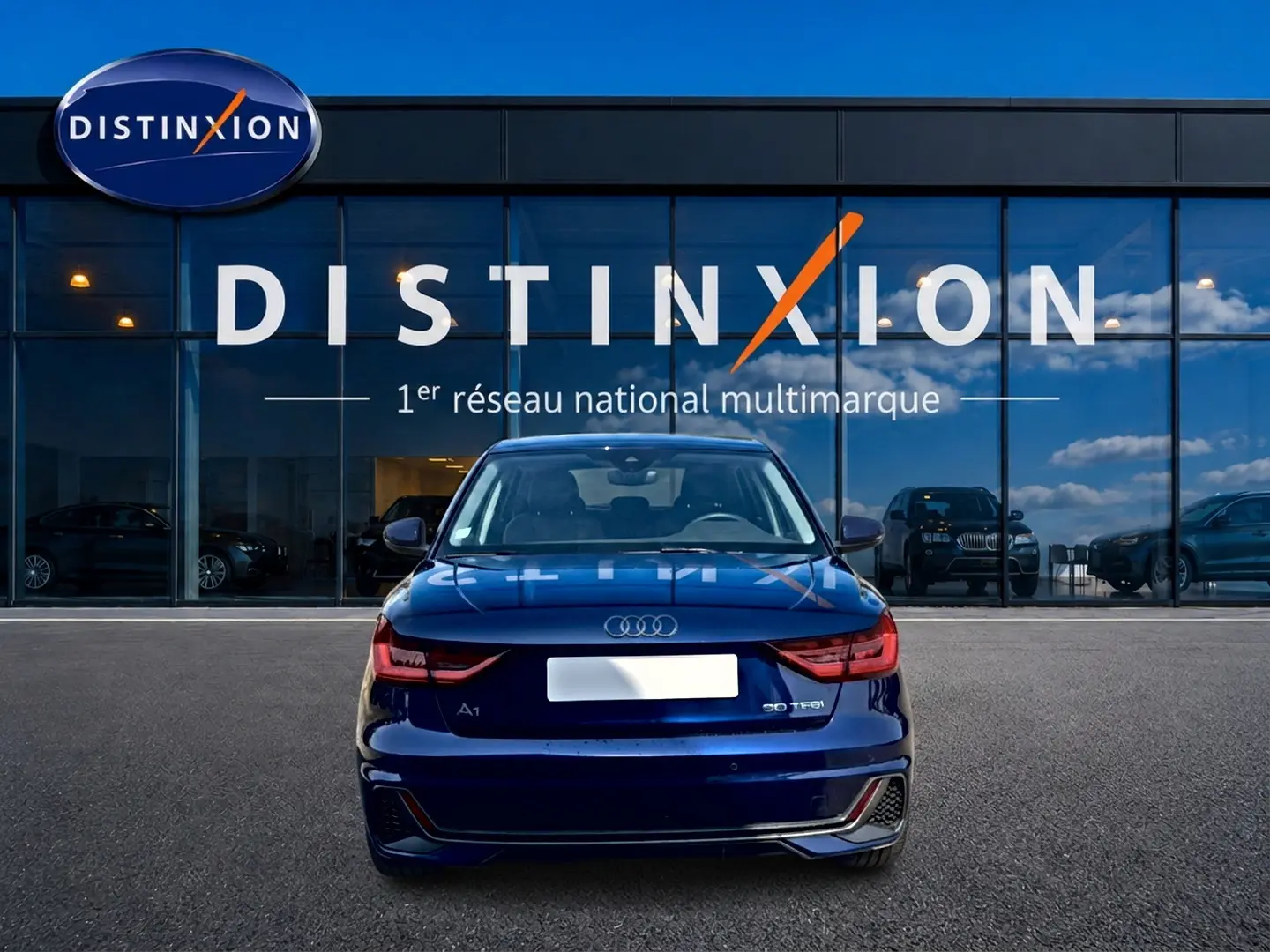 Vue arrière d'une Audi A1 Sportback 30 TFSI bleu foncé avec feux LED et becquet, devant une vitrine Distinxion.