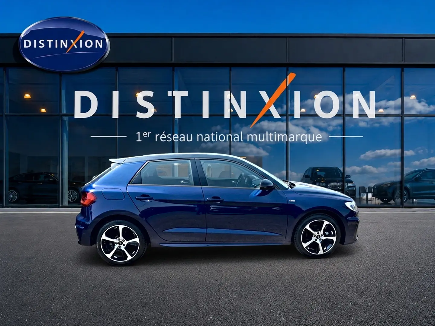 Audi A1 Sportback 30 TFSI S line bleu foncé vue de profil côté gauche devant une vitrine Distinxion.