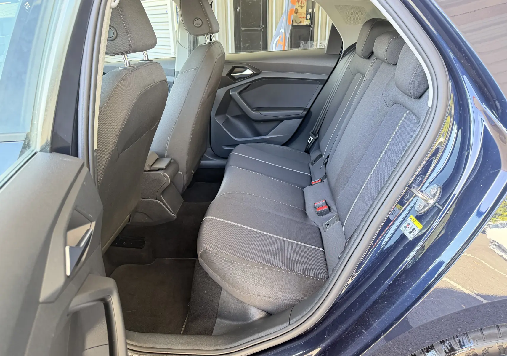 Vue intérieure côté arrière droit de l'Audi A1 Sportback 2020 bleu firmament, montrant les sièges arrière en tissu gris.