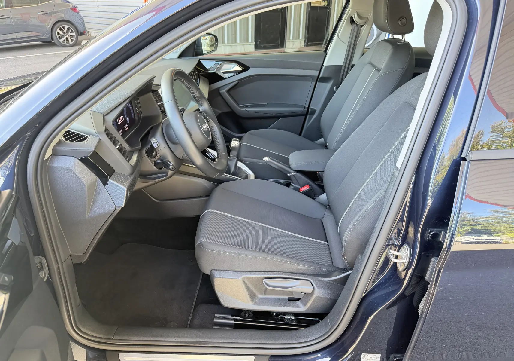 Vue intérieure côté conducteur de l'Audi A1 Sportback bleu firmament, montrant les sièges et le tableau de bord moderne.