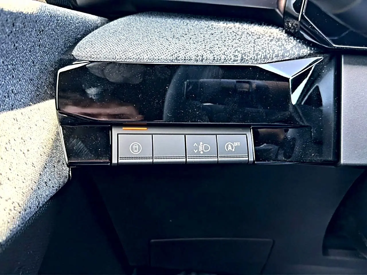 Gros plan sur les commandes de réglage des feux et du démarrage automatique dans l'habitacle d'une Renault Clio VI gris schiste.