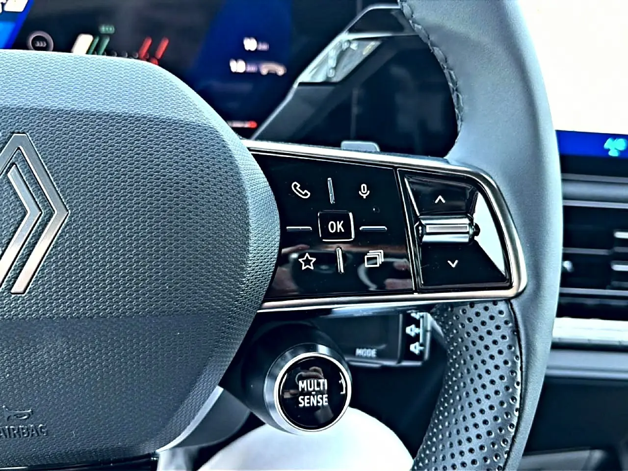 Gros plan sur la partie droite du volant gris de la Renault Clio VI avec commandes multifonctions et bouton Multi Sense.