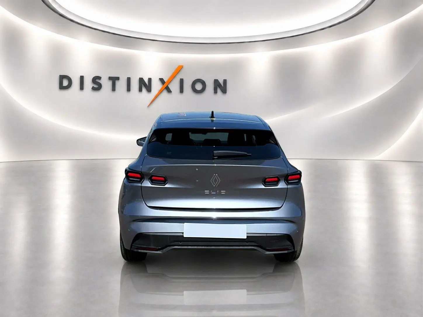 Vue arrière d'une Renault Clio VI gris schiste, avec feux arrière LED et becquet distinctif dans un showroom lumineux.