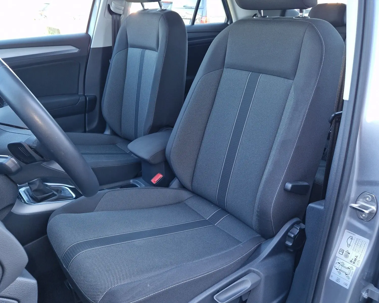 Vue intérieure côté conducteur du Volkswagen T-Roc gris pyrite 2023, mettant en valeur les sièges avant en tissu gris.