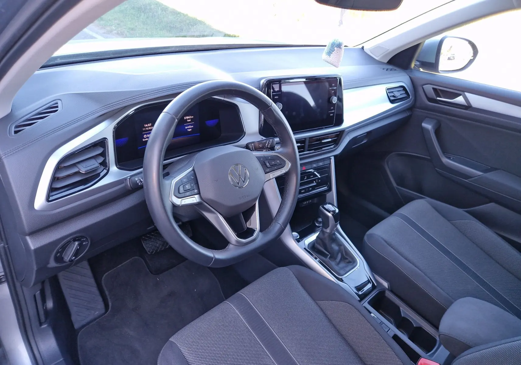 Intérieur du Volkswagen T-Roc 2023 vu côté conducteur, tableau de bord moderne avec écran tactile et volant multifonction.
