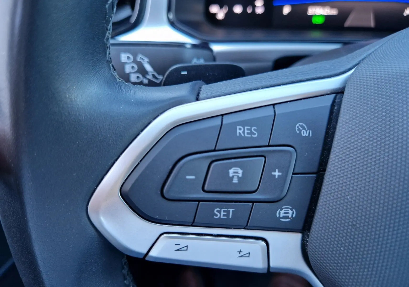 Gros plan sur les commandes du régulateur adaptatif au volant d'un Volkswagen T-Roc gris pyrite 2023.