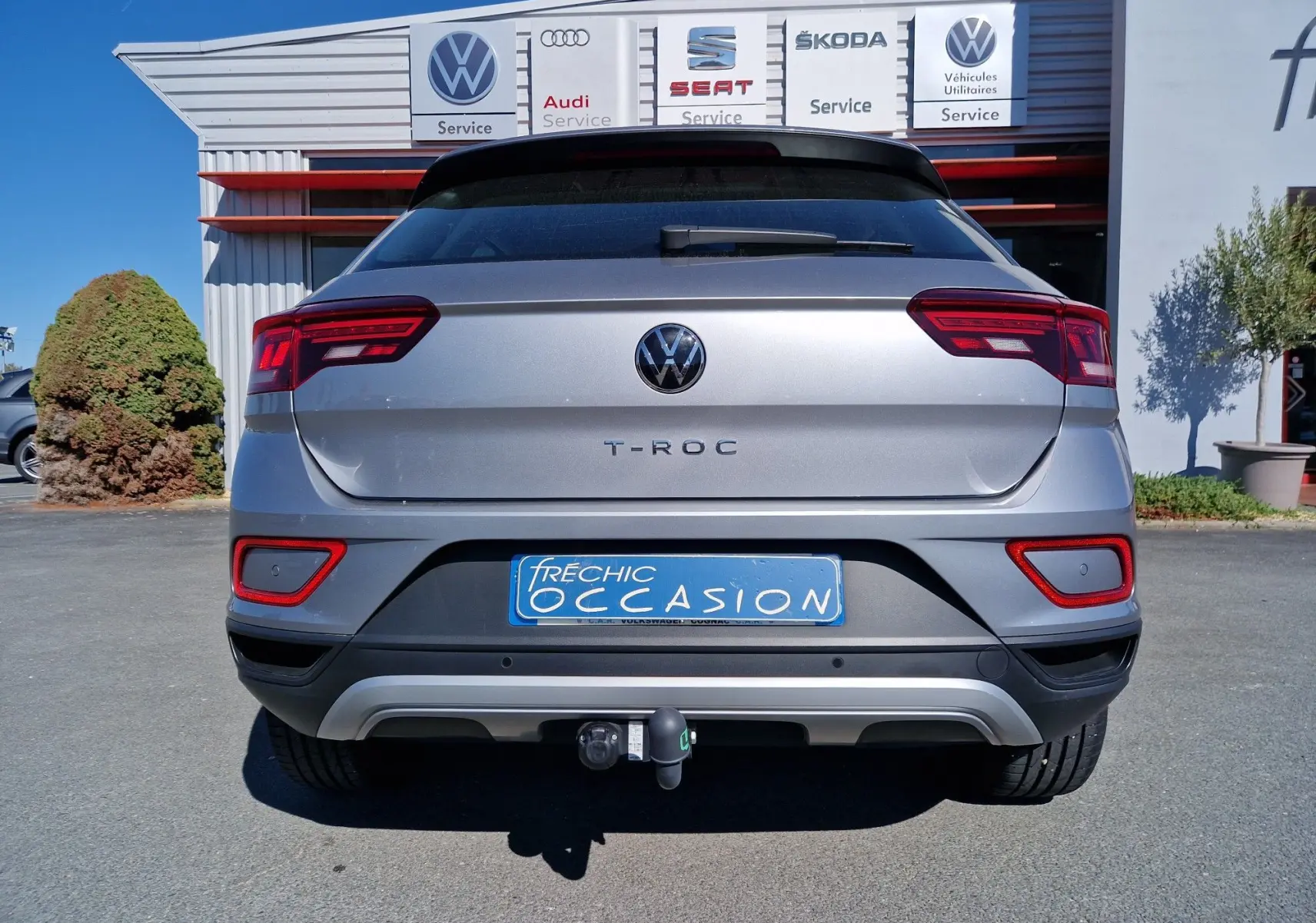 Vue arrière d'un Volkswagen T-Roc gris pyrite 2023 avec attelage et feux arrière LED visibles.