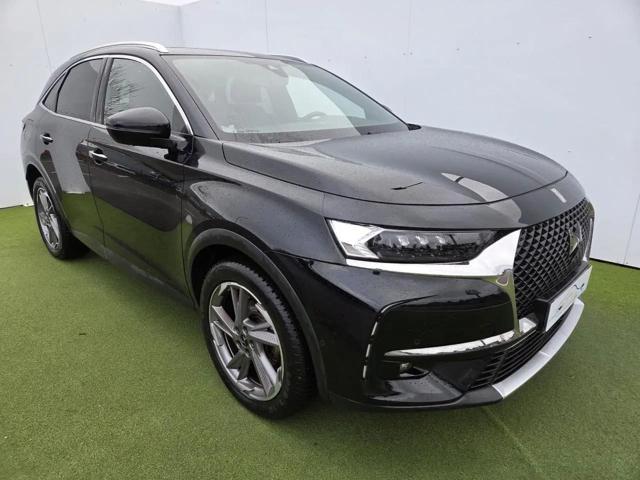 DS7 Crossback noir Perla Metal vu en 3/4 avant droit, avec calandre noire brillante et jantes alliage distinctives.