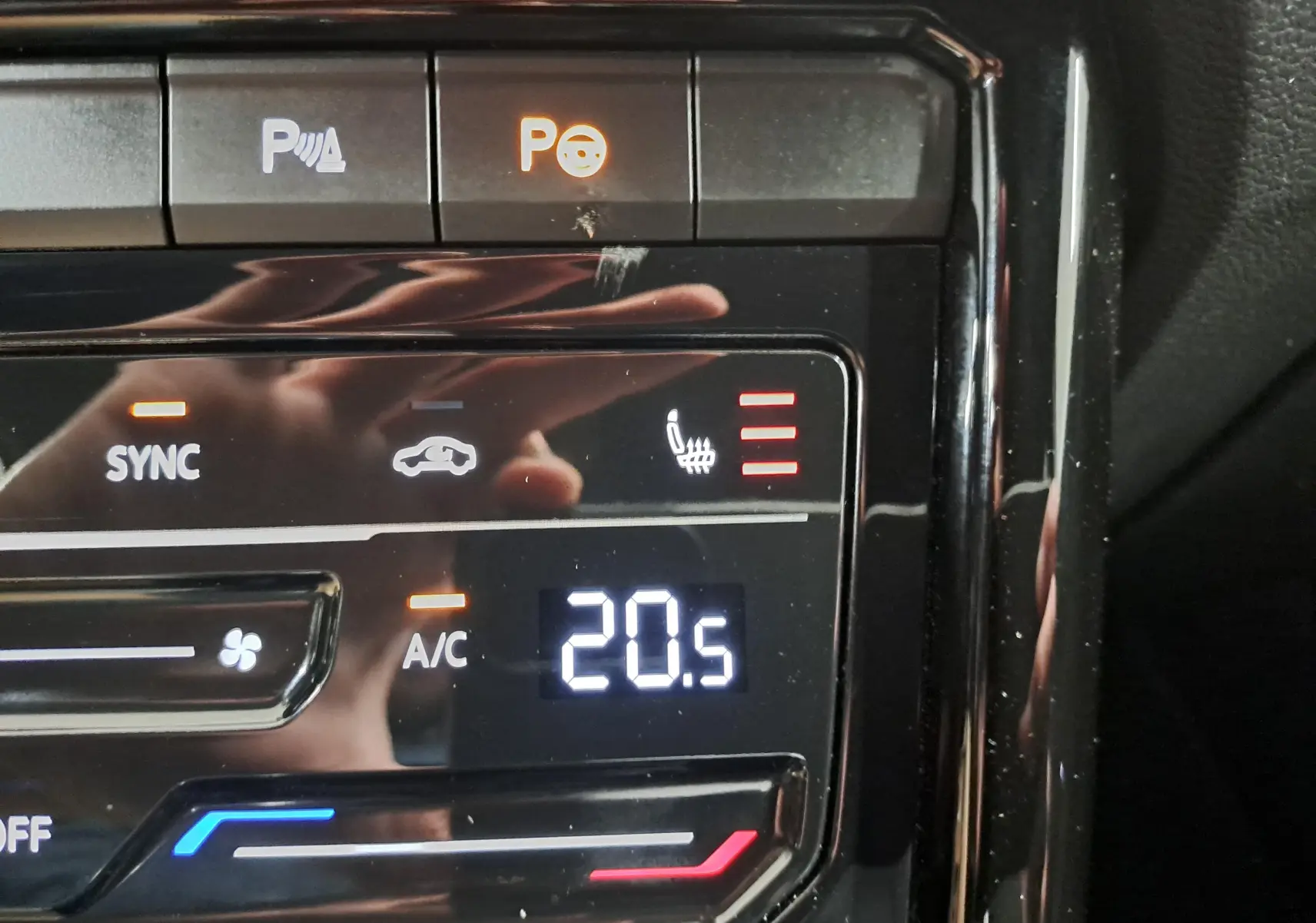 Gros plan sur la commande de climatisation avec affichage digital à 20,5°C et bouton siège chauffant actif.