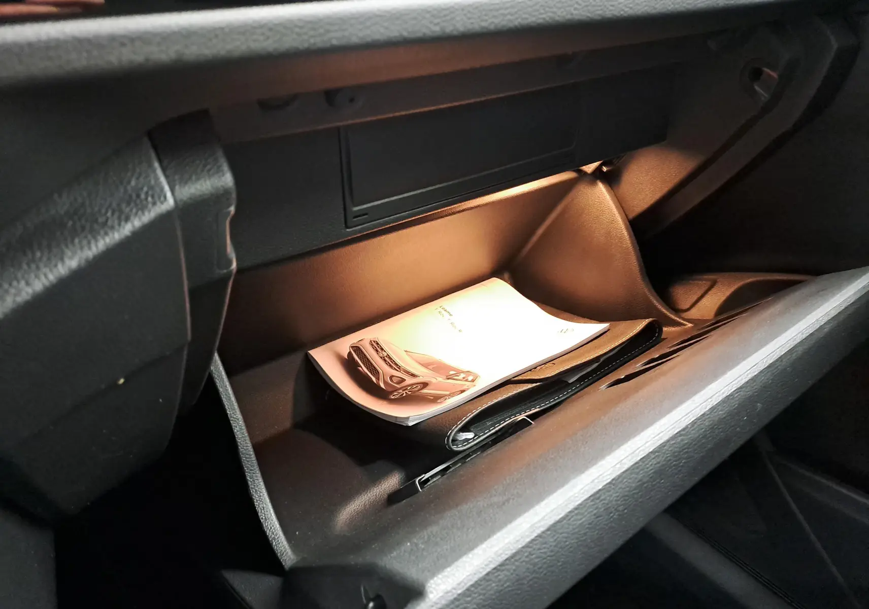 Gant de boîte à gants ouvert avec manuel et pochette dans l’habitacle du Volkswagen T-Roc 1.5 TSI Gris Pyrite.